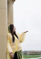 Hermosa mujer morena en impermeable amarillo atrapando lluvia al aire libre foto
