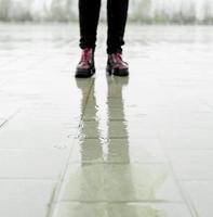 Woman walking in the rain, standing in puddles photo