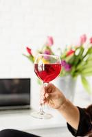 Mano de mujer sosteniendo una copa de vino tinto celebrando las vacaciones de primavera foto