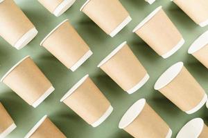 Disposable paper cups pattern top view on green background photo