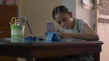 Girl using smartphone and digital tablet for learning lesson online. video