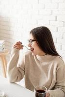 mujer sentada en la mesa blanca, comiendo pastel y tomando café foto