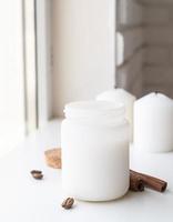 Candle with cinnamon sticks and coffee beans on white background photo