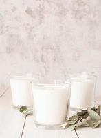 White candles with eucalyptus leaves on white wooden background photo