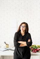 Woman working at the office, standing by the desk with arms crossed photo