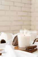 Candles with cinnamon and dry flowers on white fabric background photo