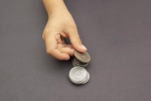 Hand putting golden and silver coin on pile of coins photo