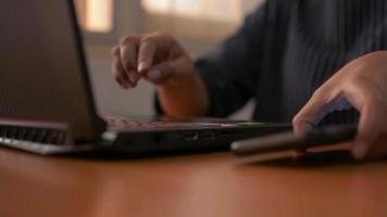 Woman typing on computer keyboard and using smartphone on working desk video