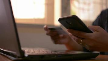 mujer de compras en línea en el teléfono inteligente con tarjeta de crédito en casa. video