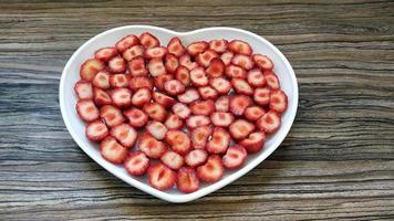 The sliced strawberries are in a heart-shaped plate photo