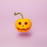 calabaza de halloween con cara feliz sobre fondo rosa mínimo foto