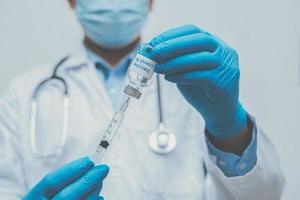 mano de médico en guantes azules con coronavirus, vacuna covid-19 foto