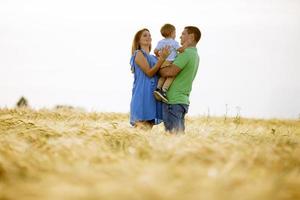 Familia joven con lindo niño divirtiéndose al aire libre en el campo