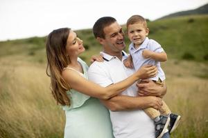 Familia joven con lindo niño divirtiéndose al aire libre en el campo foto