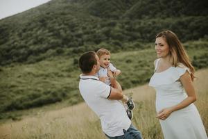 Young family with cute little boy having fun outdoors in the field photo