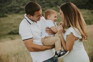 Young family with cute little boy having fun outdoors in the field photo