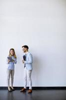 jóvenes empresarios con tableta junto a la pared en la oficina foto