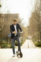 Young businessman using mobile phone  on electric scooter photo