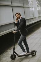 Young businessman using mobile phone  on electric scooter photo