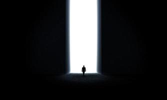 Silhouette of businessman standing in front of lighting door photo