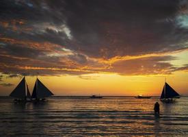 Hermoso atardecer tropical con veleros y turistas en la isla de Boracay, Filipinas foto