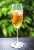 Orange liqueur and champagne cocktail in glass outside in garden photo