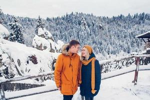 Couple cuddling outdoors in snow landscape wearing heavy winter coats