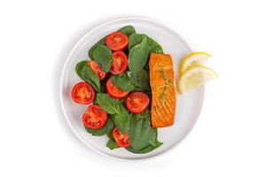 Piece of fried trout with tomatoes and spinach leaves photo
