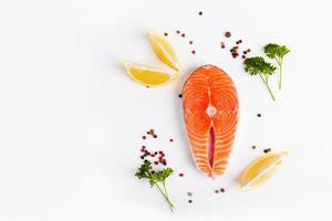 Salmon steak with pepper and lemon wedges on a white plate photo