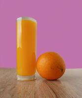 Vaso de jugo de naranja y naranjas sobre un piso de madera foto