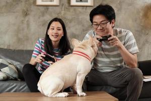 pareja asiática está jugando videojuegos y un perro mascota cerca.