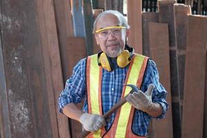 Male Asian elderly carpenter in wooden facory. photo