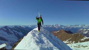 um alpinista de esqui na mochila chega ao topo da montanha video