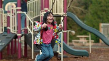 Young girl swinging at park in slow motion video