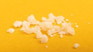 Piezas de cristal de cera de concentrado de marihuana, toque de cannabis sobre fondo amarillo. foto