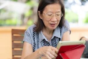 Senior mujer asiática con tableta digital en casa foto