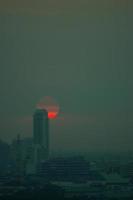 The red sun in the evening clouds And tall buildings in big cities photo