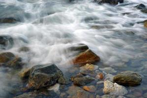 turbulencia de agua de mar y rocas en la costa foto