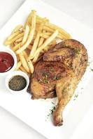 Roast rotisserie half chicken with french fries simple meal on white plate photo