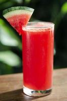 Glass of fresh organic watermelon juice on garden table outdoors on sunny day photo