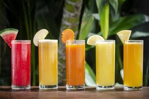 Selección de vasos de jugo de fruta orgánica fresca mixta en la soleada mesa de jardín foto