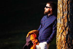 Young man with beard resting on a plant photo