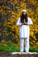 mujer de blanco practica yoga en la naturaleza en otoño foto