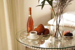 Glass table with a cup of coffee, sweet croissants photo