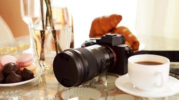 Photo camera with a lens on glass table. Cup of coffee