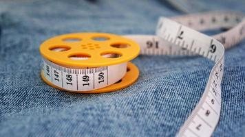 Blue jeans and a measuring tape. Slimming or sewing denim concept