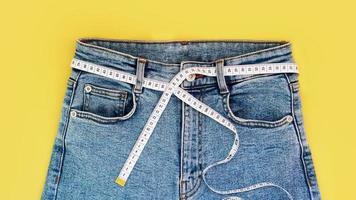 Measuring tape and jeans on a bright yellow background photo