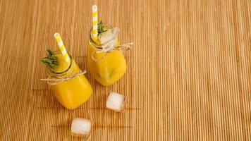 botellas de jugo de naranja y pajitas de papel. bebida helada en un día soleado foto