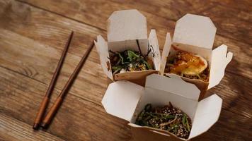 Noodles with pork and vegetables in take-out box on wooden table photo
