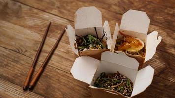 Noodles with pork and vegetables in take-out box on wooden table photo